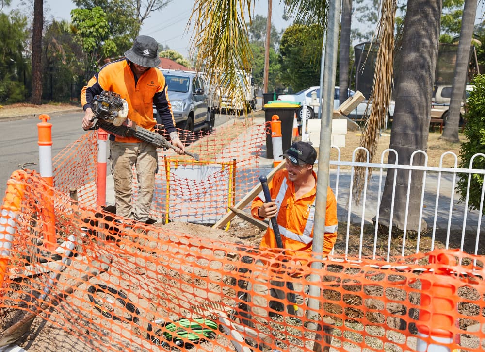 Two workers digging with shovel and jackhammer